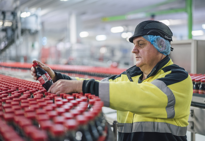 Betriebsleiter: Ralf Schmalenbeck prüft die Coca-Cola Flaschen mit neuem Deckel am Produktionsband.
