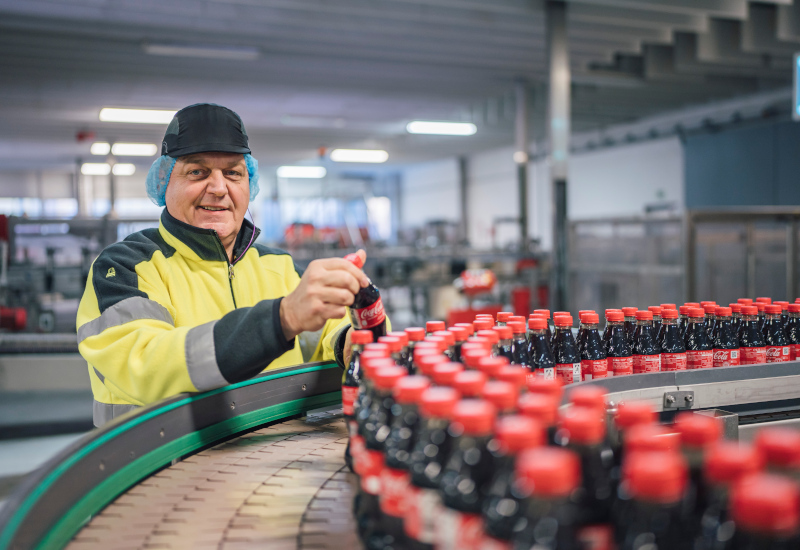 Betriebsleiter Ralf Schmalenbeck prüft Coca-Cola Flaschen am Produktionsband
