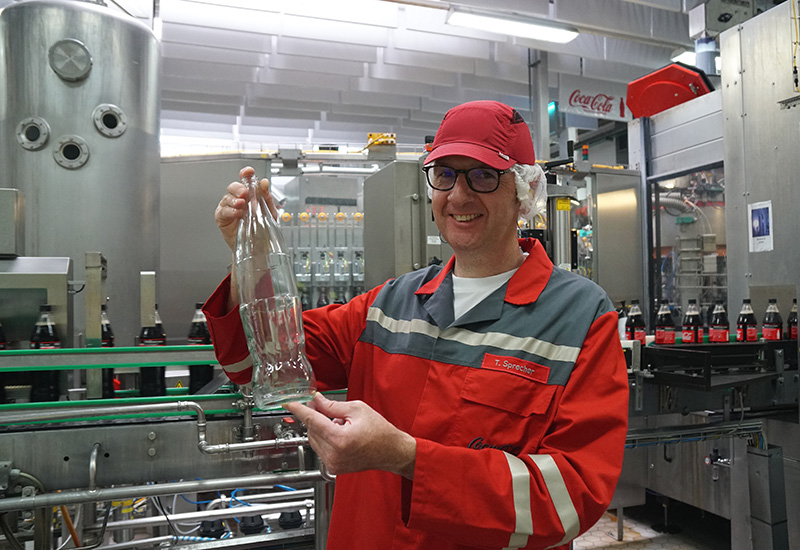 Coca-Cola Betriebsleiter Thomas Sprecher zeigt die 1-Liter-Glasflasche