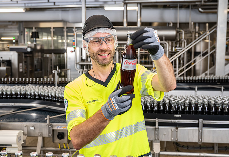 Mitarbeiter prüft Coca-Cola Glasflasche