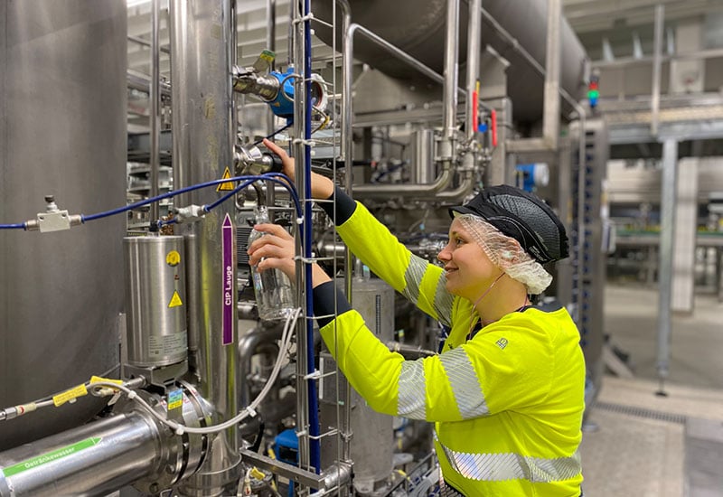 Coca-Cola Mitarbeiterin entnimmt Spülwasser am Produktionsstandort in Karlsruhe