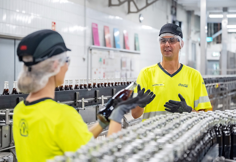 Coca-Cola Abfüllung in Mannheim: Betriebsleiter Christopher Bee unterhält sich mit Produktionsmitarbeiterin über Coca-Cola Glasflaschen
