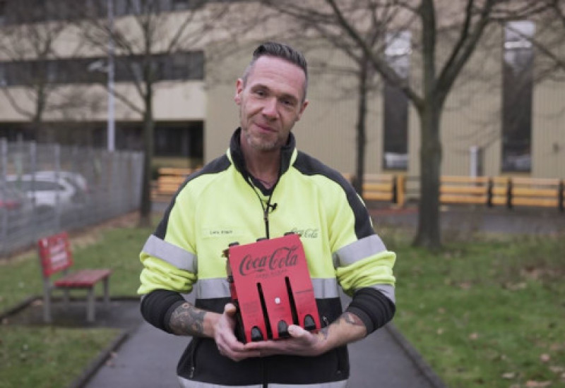 Projektleiter Lars Krack mit einem Coca-Cola Sixpack in den Händen