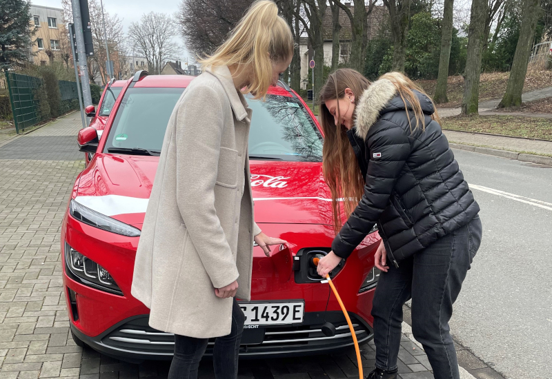 Coca-Cola Nachhaltigkeit: Alina mit Kollegin Lena beim Auftanken eines E-Autos
