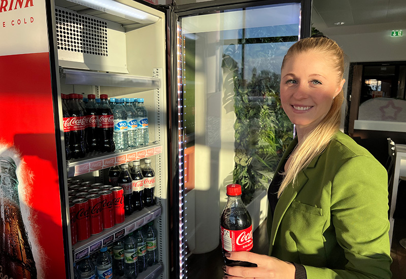 Alina Walther nimmt eine Coca-Cola Flasche aus dem Kühlschrank
