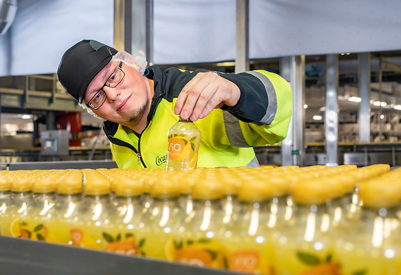 Coca-Cola Produktion in Lüneburg: Mitarbeitender prüft Abfüllung der ViO Getränkeflaschen