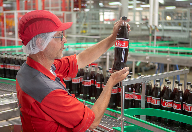 Coca-Cola Mitarbeiter kontrolliert Flasche in der Produktion