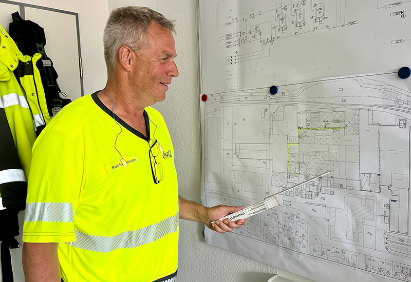 Arbeiten bei Coca-Cola: Ralf Bockelmann mit einem Zollstock vor dem Grundriss-Plan zum Umbau