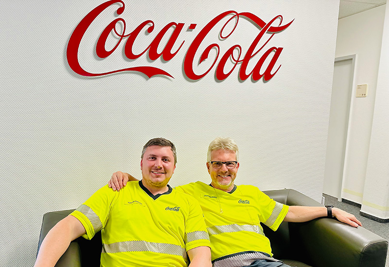 Betriebsleiter Johannes Bleker und Valentin Batrakin sitzen auf der Coach im Coca-Cola Werk in Mölln