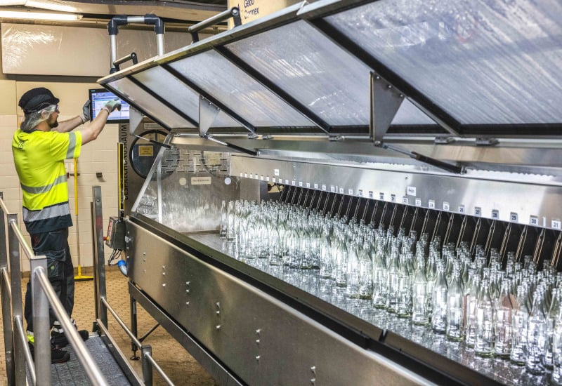 Ein Coca-Cola-Mitarbeiter am Standort Fürstenfeldbruck bedient die Flaschenreinigungsmaschine für Mehrwegflaschen.