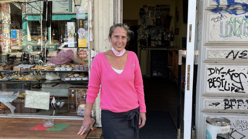Fatima Amorim steht vor dem Eingang zu ihrem Café MIP im Hamburger Schanzenviertel. Sie trägt einen pinkfarbenen Pullover und schaut in die Kamera.